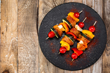 Raw shashliks on black stone plate