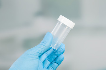 Hand in medical gloves holds a medical probe container