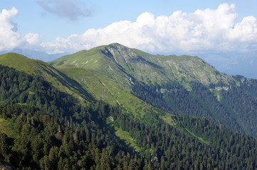 Green mountain peaks covered by forest against a background of clouds. Abkhazia.