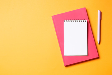 Notebook with pen on an orange background.
