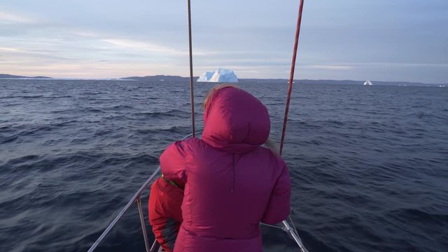 Woman on ship's bow taking picture from camera at Disko Bay