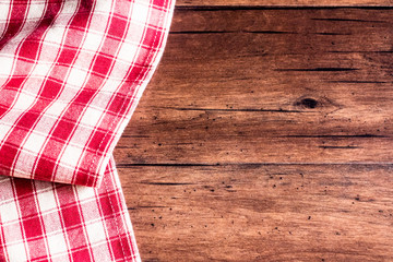 Checkered red napkin on an old wooden brown background, top view. Image with copy space. Kitchen table with a towel - top view with copy space. 