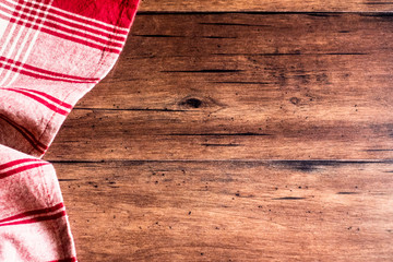 Striped red and white napkin on an old wooden brown background, top view. Image with copy space. Kitchen table with a towel - top view with copy space. 