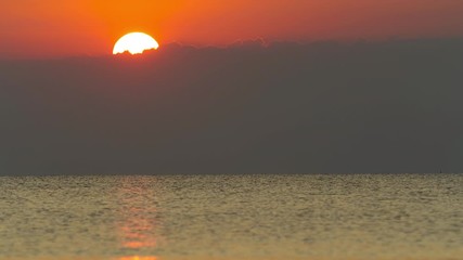 Time lapse of the large sunset as the sun sets into the horizon above the sea.