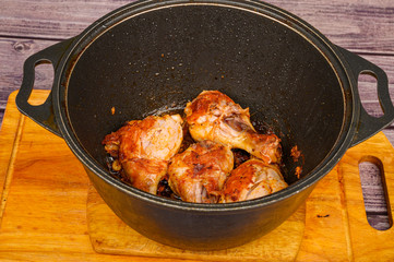 Chicken legs marinated with spices are fried in a cauldron