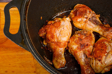 Chicken legs marinated with spices are fried in a cauldron