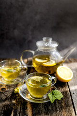 Herbal tea with lemon and honey in glass cup and teapot on sunny day light