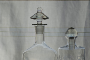 zwei dekorative Glasflaschen vor strukturiertem Hintergrund weiß grau platz für text