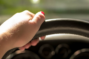 Woman driving a car with one hand holding the steering wheel