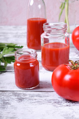 Tomato juice in glass jars on white wooden table