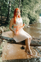 Fototapeta na wymiar cute redheaded girl walking in the summer hot city park