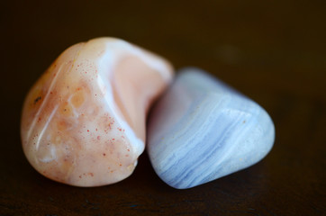 Blue Lace Agate and Banded Carnelian on display with fresh flowers and plants. Healing crystals and nature, plants on a wooden desk. Blue and orange reiki healing stones.  