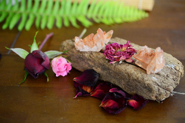 Tangerine Quartz cluster on wooden slab. Roses and healing crystals on display, bohemian decorations. Metaphysical witchy healing display. Crystal collection with flowers.