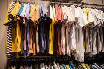Suit shop, Raw of different colors man's suit or jackets hanging on apparel which blurred backgrounds