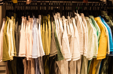 Suit shop, Raw of different colors man's suit or jackets hanging on apparel which blurred backgrounds