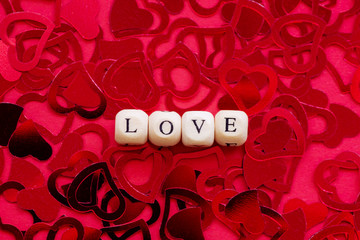 Word love, wooden cubes letters, on a red background whit red hearts