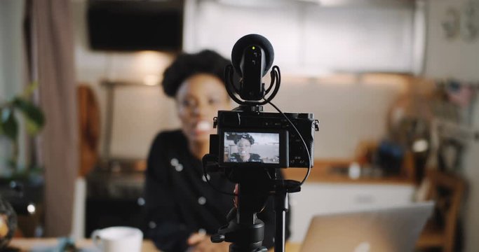 Close-up professional camera is filming young beautiful African blogger woman creating new vlog video slow motion.