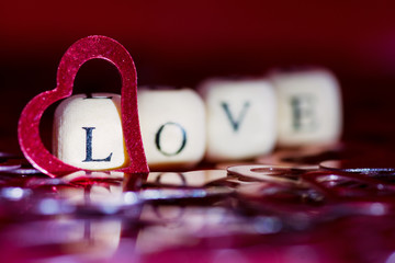 Word love, wooden cubes letters, on a red background whit red hearts