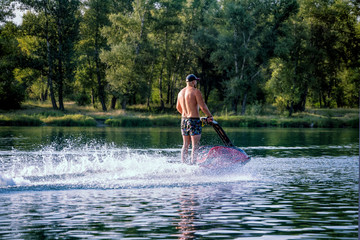 Young man riding water scooter at sea lake river on summer day.