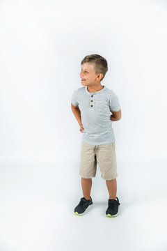 Little boy with autism standing on a white background feeling happylooking to the side