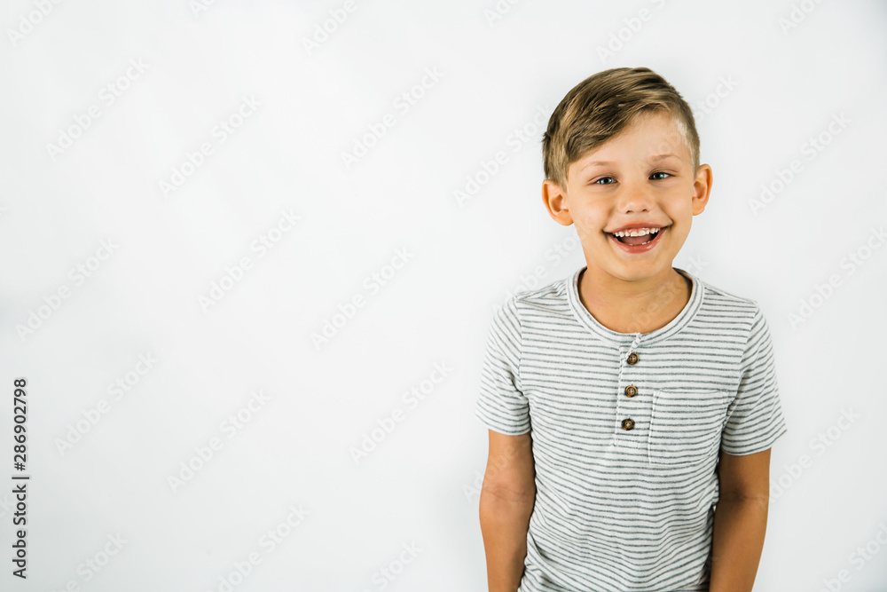 Wall mural little boy with autism standing on a white background feeling happy and smiling