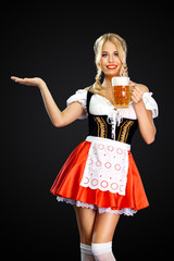 Smiling sexy oktoberfest girl waitress, wearing a traditional Bavarian or german dirndl, serving...