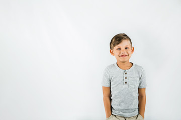 Little boy with autism standing on a white background feeling happy and smiling
