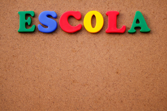 Word "Escola" (school in portuguese) written in colorful plastic letters on a wooden background.