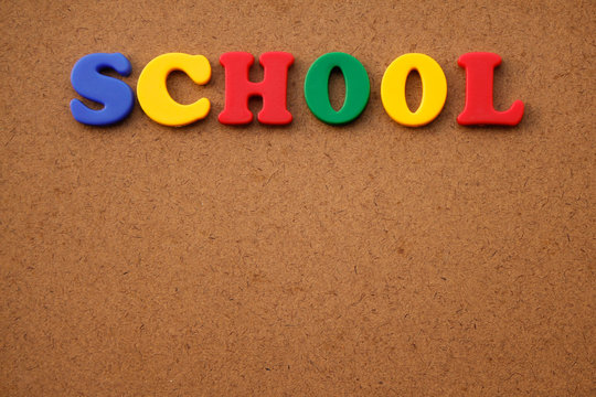 Word "School" written in colorful plastic letters on a wooden background.