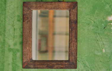 Mirror in a wooden frame on a green wall