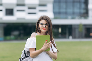 Obraz premium Woman uses tablet computer stand near business center. Attractive technology girl. Young woman work screen smart. Professional holding portrait