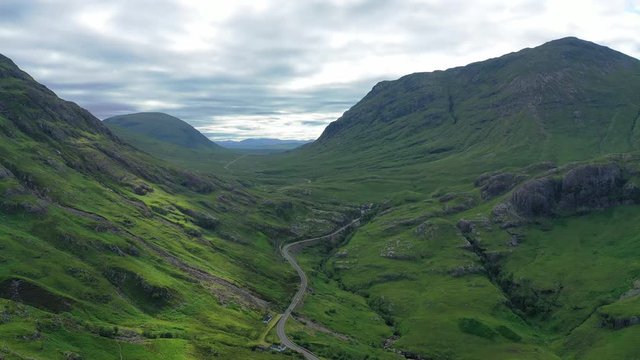 Aerial view of picturesque landscape of Glen Coe, scenic lush green valley surrounded by rocky hills of Highlands of Scotland - panorama of Scotland from above, United Kingdom, Great Britain, Europe