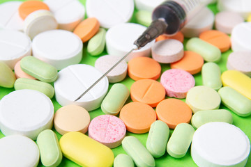Medicines pills, drugs and antibiotics on a green background. Medicine and health care.