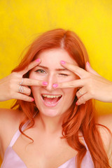 pretty playful plus size red-haired adult girl with arms palms and bright beauty nails near face.