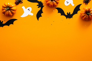 Happy halloween holiday concept. Halloween decorations, pumpkins, bats, ghosts on orange background. Halloween party greeting card mockup with copy space. Flat lay, top view, overhead.