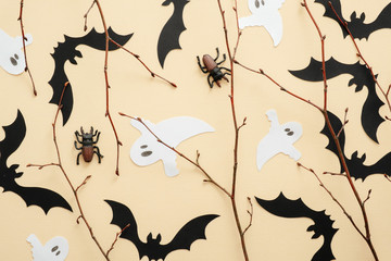 Happy Halloween concept. Halloween decorations, bats, ghosts, spiders on pastel beige background. Halloween party greeting card. Flat lay, top view, overhead.