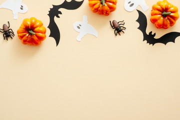 Obraz na płótnie Canvas Halloween composition. Halloween decorations, pumpkins, paper ghost, spiders on pastel beige background. Halloween concept. Flat lay, top view, copy space