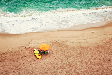 umbrella and surf board at the seashore with waves breaking