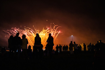 Fototapeta premium people look at the festive bright fireworks in the night sky