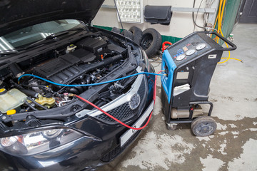 The procedure for refueling a car air conditioner using a special device with a blue compressor and...