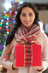 Woman with gift and christmas tree in the background