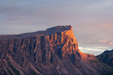 Golden glowing Ponta Lastoi de Formin during sunset with pale grey sky