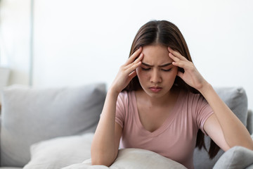 Young woman holding her hands on the forehead and have a headache on the sofa.