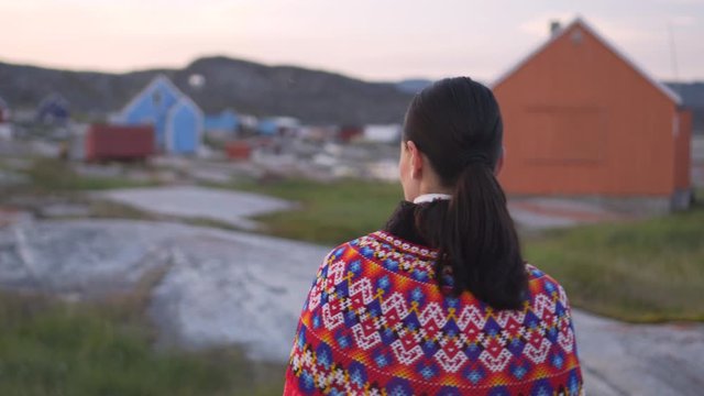 Female in indigenous costume walking on landscape in village - Disko Bay, Greenland
