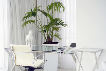 Interior of the hotel's living room. Beautiful writing desk. White interior concept of the apartment. Modern interior of the office in a luxury villa. White color, large window.