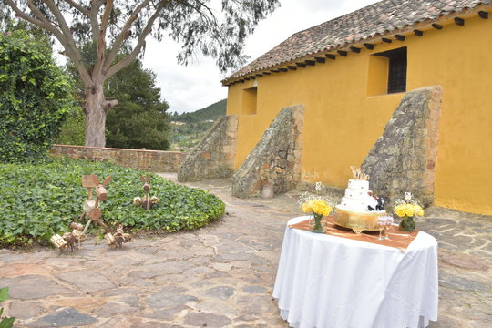 ponque en mesa detras de casa antigua jardin y arboles campestre