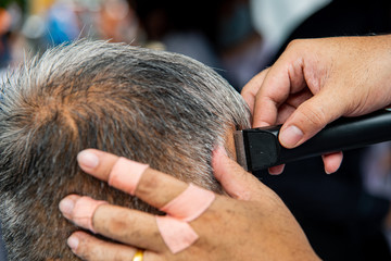 Hairdresser use hair clipper doing haircut for old man.