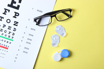 a table for checking vision, glasses and lenses for correcting vision on a colored background, top view. Ophthalmologist Accessories.
