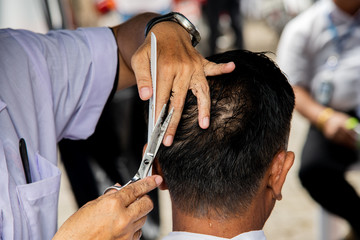 Hands of hairdresser use comb and scisscors doing haircut in communiter center.