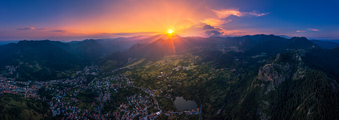 Panoramic view of a romantic sunset over rocky mountains and small city 